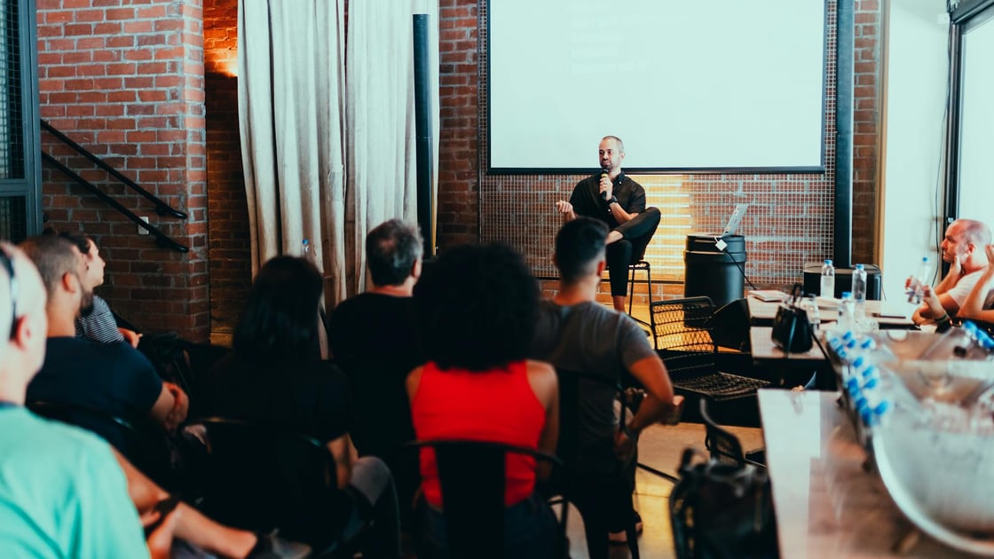 A man sitting on stage at a tech conference giving a talk